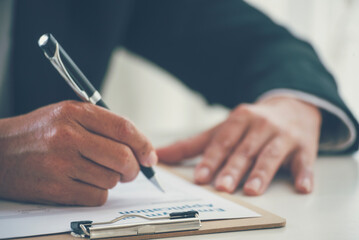 Fototapeta premium Businessman hand using pen signing on new contract starting projects in conference room. Close up business manager man hands sign contract legal document in meeting room. Business agreement concept