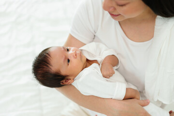 mother holding and talking with her newborn baby on bed