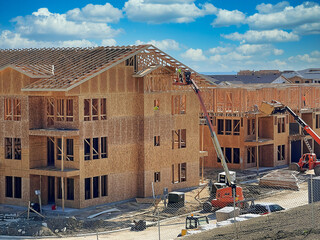 Hard working team constructing multi-family housing apartments: Construction workers utilizing...