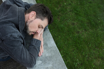 Tired man sleeping on stone parapet outdoors, top view. Space for text