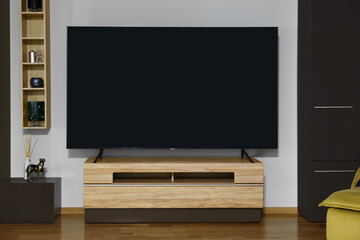 Modern plasma TV on wooden table and other furniture in living room