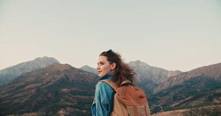 Young caucasian girl going for an adventure, hiking in beautiful mountains, having an active...