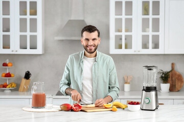 Fototapeta na wymiar Handsome man preparing ingredients for tasty smoothie at white marble table in kitchen