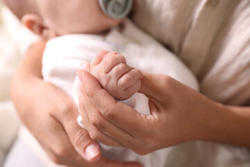 Fototapeta na wymiar Mother holding newborn baby indoors, focus on hands