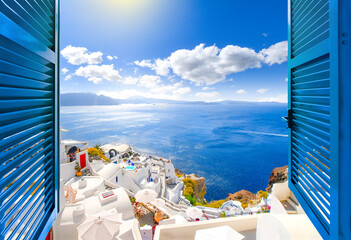 Hillside view through an open window with blue shutters of the caldera, sea and white village of Oia on the island of Santorini, Greece.	 - obrazy, fototapety, plakaty