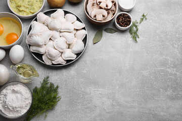 Fototapeta na wymiar Raw dumplings (varenyky) and ingredients on grey table, flat lay. Space for text