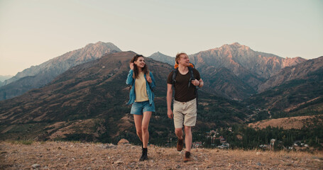 Young couple having an adventure, exploring beautiful mountains, hiking with backpacks, having an active vacation - active lifestyle, freedom concept 