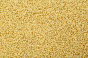 Raw couscous grains as background, top view