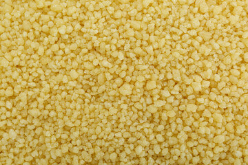 Raw couscous grains as background, top view