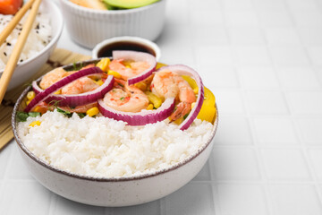 Delicious poke bowl with shrimps, rice and vegetables on white table, closeup. Space for text