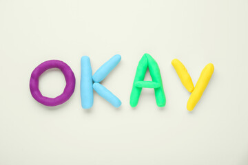 Word Okay made of colorful plasticine on white background, top view