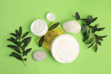 Fototapeta na wymiar Different cosmetic products with olives and stones on light green background, flat lay
