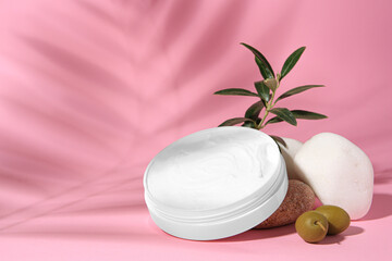 Fototapeta na wymiar Jar of natural cream, stones and olives on pink background. Cosmetic products