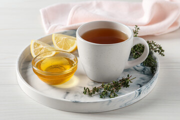 Obraz na płótnie Canvas Aromatic herbal tea with thyme, honey and lemons on white wooden table