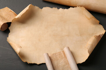 Sheets of old parchment paper on grey wooden table