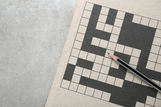 Blank crossword and pencil on old white table, top view. Space for text
