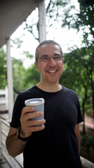 man drinks coffee and talks on cell phone on an office balcony on a rainy day