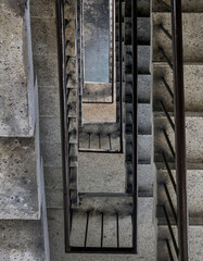 View from above of concrete spiral staircases pattern of square shape are in the old building architecture, Looking down at interior ground floor of old building which are deteriorated over time.