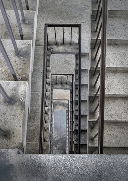 View From Above Of Concrete Spiral Staircases Pattern Of Square Shape Are In The Old Building Architecture, Looking Down At Interior Ground Floor Of Old Building Which Are Deteriorated Over Time.