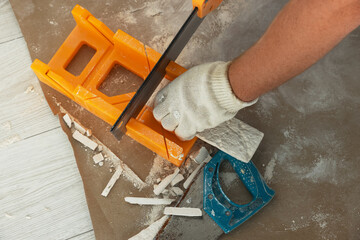 Worker cutting decorative wall tile indoors, closeup