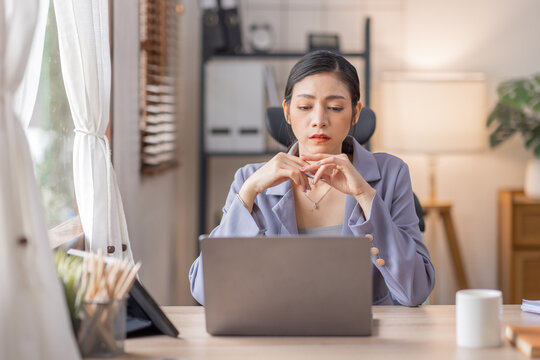 Happy Young Asian woman using laptop while working at home with documents. online documentation calculator to calculate the numbers, finance accounting office concept