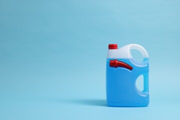 Plastic canister with color liquid on light blue background. Space for text