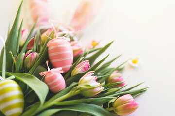 Happy Easter. Stylish dyed easter eggs with spring flowers on white background. Pink tulips with...