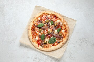 Tasty pizza with anchovies, basil and olives on white table, top view