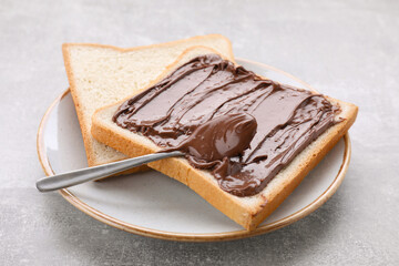Tasty breakfast. Toast with chocolate paste served on grey textured table, closeup