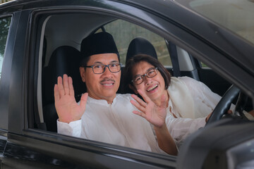 Indonesian husband and wife, waving their hands to say good bye from inside car cabin