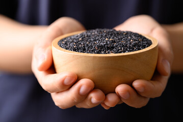 Black sesame seed in bowl holding by hand