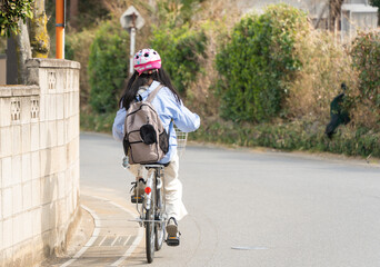 ヘルメットを被って自転車に乗る小学生の女の子