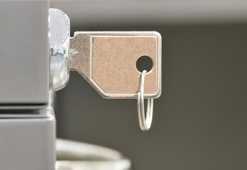 Key in office filing cabinet lock concept side view closeup copy space selective focus.