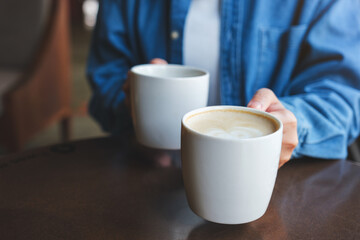 Closeup image of a woman holding and serving two cups of hot coffee