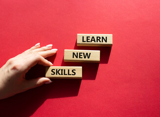 Learn new skills symbol. Concept words Learn new skills on wooden blocks. Beautiful red background. Businessman hand. Business and Learn new skills concept. Copy space.