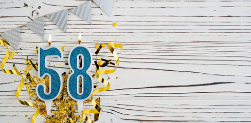 Number 58 blue celebration candle on white wooden background. Happy birthday for fifty-eight years old. Copy space.