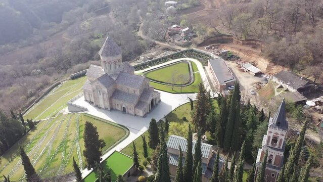 Scenic spring aerial view of monastic complex of Bodbe nunnery on hillside among tall Cypress trees with Church of St. Nino on sunny day, Sighnaghi, Georgia