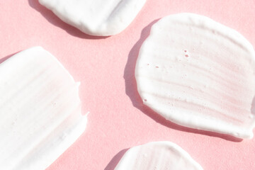 Smears of white cosmetic texture on a pink background top view. Cream, lotion, soap for hygiene and care.