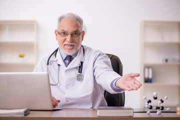 Old male doctor studying molecular model at the hospital
