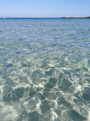 Fig Tree Bay beach, crystal clear water, white sand at the bottom, small island off the coast.