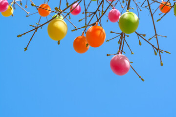 Background with colorful easter eggs on branches and blue sky