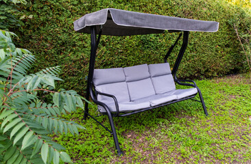 vue sur une chaise berçante grise sur une structure en métal noire en été dans le jardin