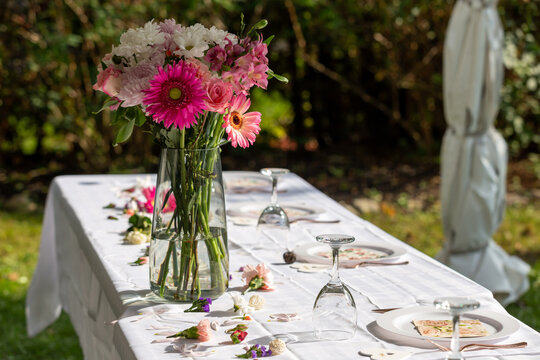 bouquet de fleurs roses et blanches dans un vase sur une longue table avec une nappe blanche à l'extérieur