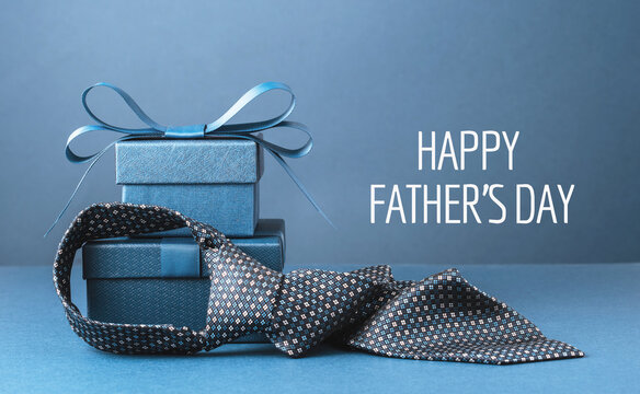 Happy Fathers Day text background banner. Two blue gift boxes with ribbon bow and necktie on dark blue table. Monochrome. Gift delivery for him. Male fashion. Greeting card