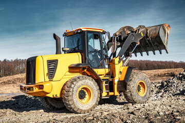 Fototapeta na wymiar Powerful wheel loader or bulldozer working on a quarry or construction site. Earthworks in construction. Powerful modern equipment for earthworks.