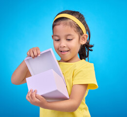 Box, surprise and child with gift in studio on blue background for present, birthday or celebration. Happiness, smile and isolated young, excited and happy girl opening package, product and parcel
