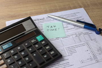 Tax time! Overhead view of work desk with keyboard, calculator, pen and income tax return form. 