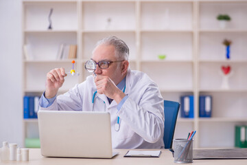 Old male doctor holding molecular model in the clinic