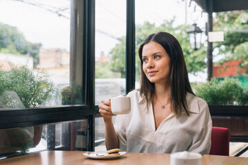 Portrait of cheerful young girl enjoying a cup of coffee. Pretty smiling girl drinking hot tea in winter