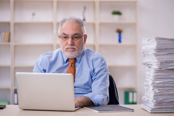 Fototapeta premium Old male employee unhappy with excessive work in the office